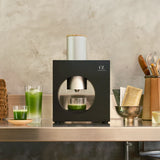Black kitchen appliance on a countertop with green juice in glasses.