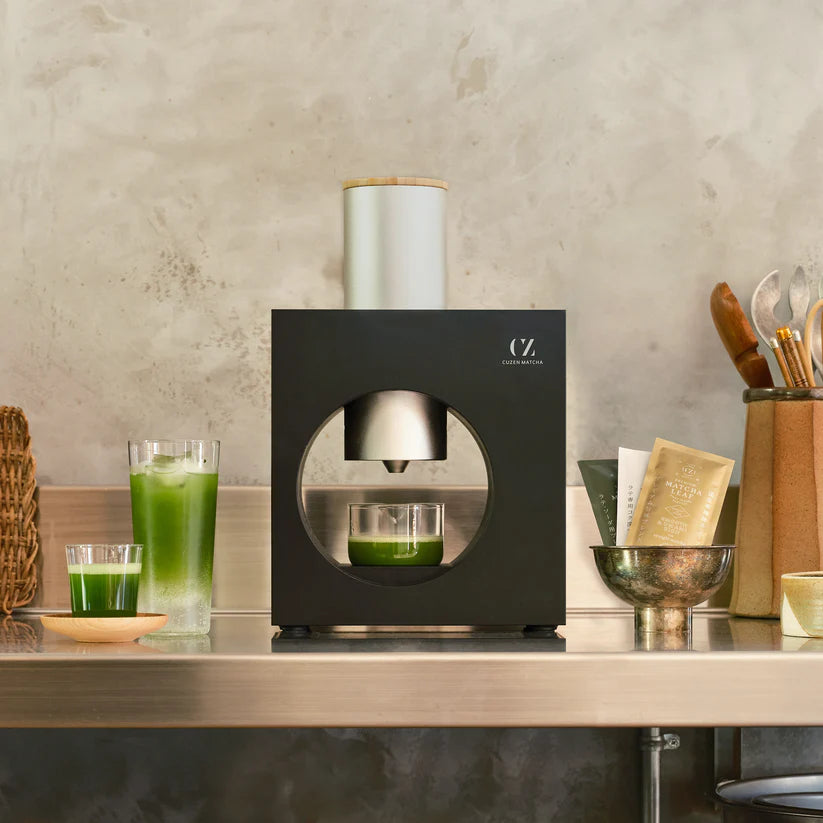 Black kitchen appliance on a countertop with green juice in glasses.