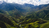 Valley with a river winding through green mountains under a cloudy sky