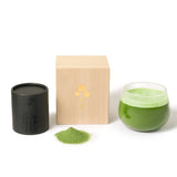 Matcha green tea set with black container, wooden box, and glass on a white background