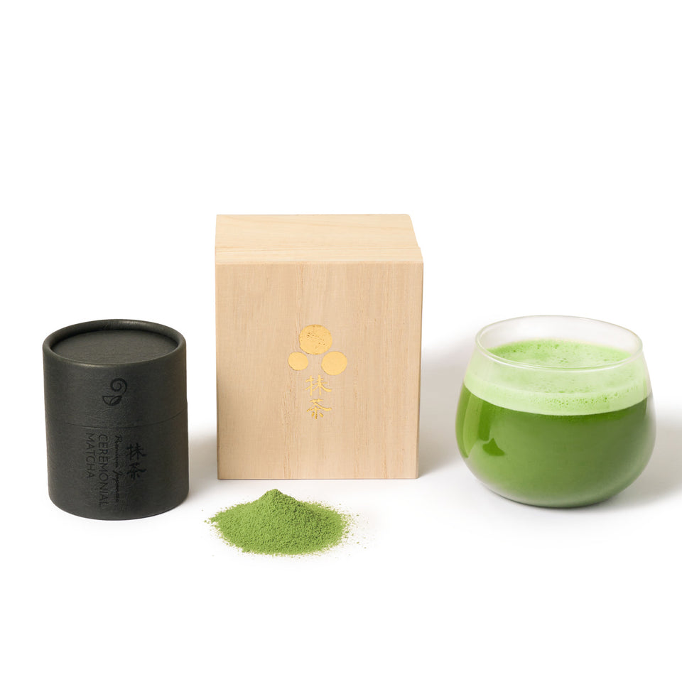 Matcha green tea set with black container, wooden box, and glass on a white background